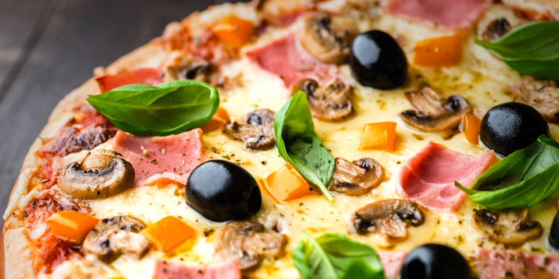 Pizza med skinka, ost, champinjoner, oliver och basilika